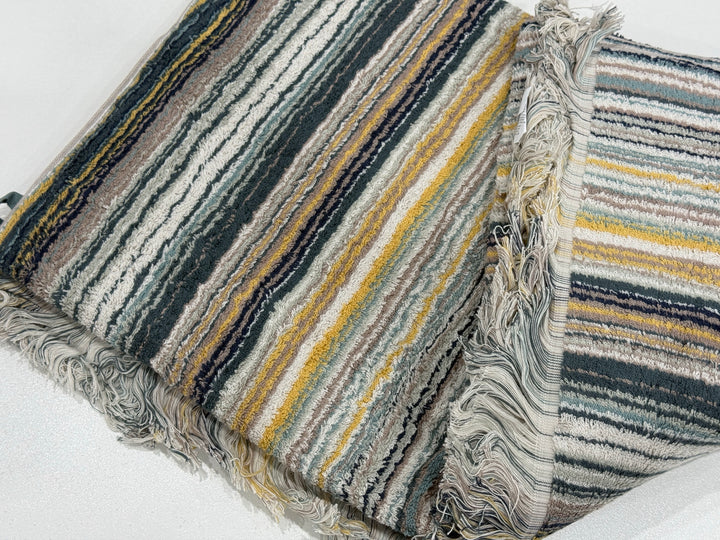 Luxury Bedsy Striped Fringed Cotton Towel displayed in a bathroom and beach setting, lightweight, absorbent, quick-drying towel with boho-style fringed edges.